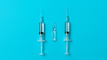 Two dialed syringes with a medicine and with an ampoule with a medicine on a blue background